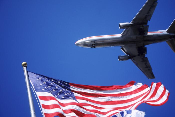 Airplane and American Flag flying in the sky. 