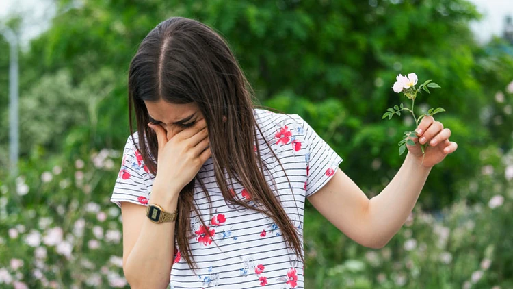 A woman sneezing from flower pollen.