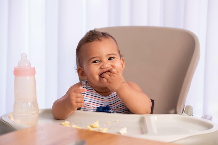 Baby eating eggs in high chair