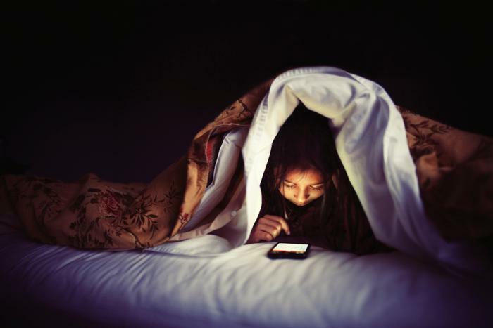 Child using phone at night in bed 
