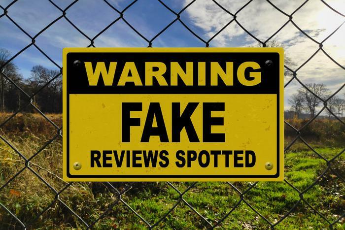 Fake reviews warning sign on fence