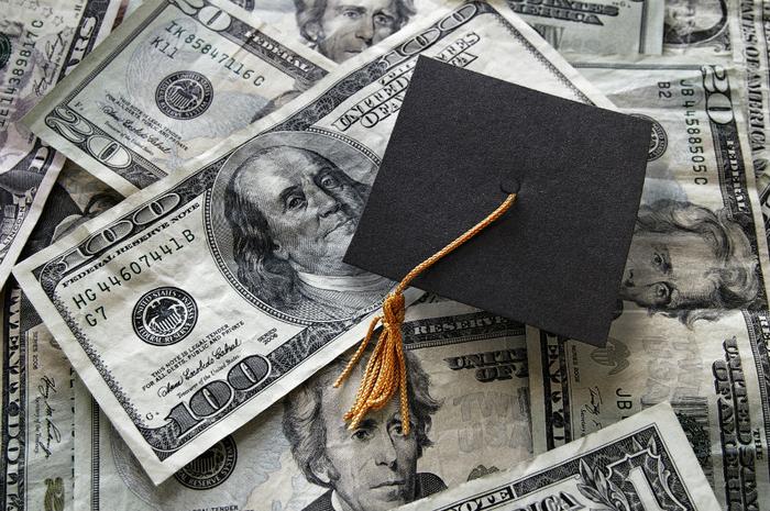 Graduation cap on money student loan debt concept