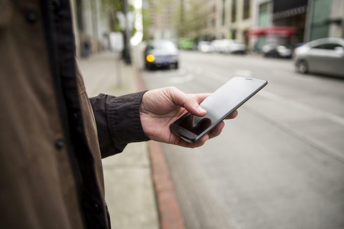 Man holding smartphone on sidewalk