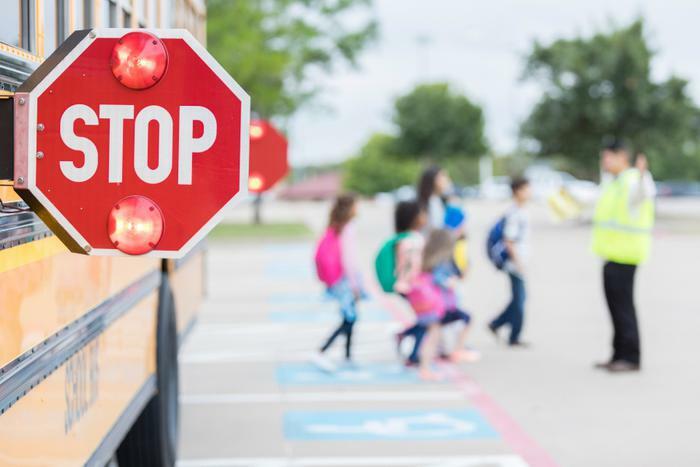 School bus stop sign with kids walking in crosswalk