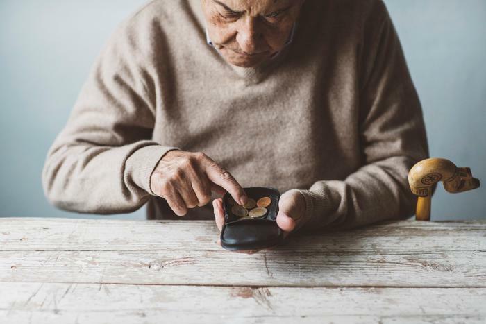 Senior man counting coins in wallet