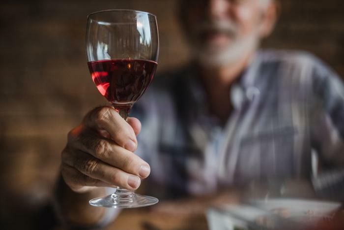 Senior man holding glass or red wine