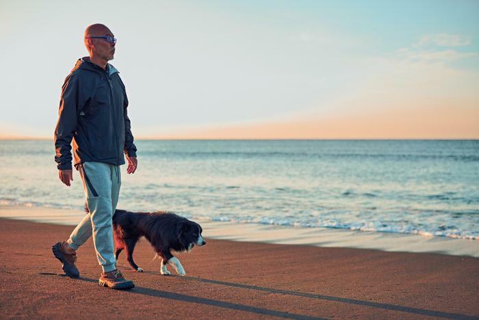Senior walking on beach with dog concept