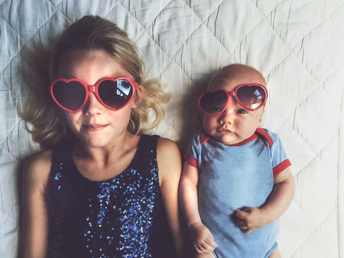Siblings lying on bed with sunglasses