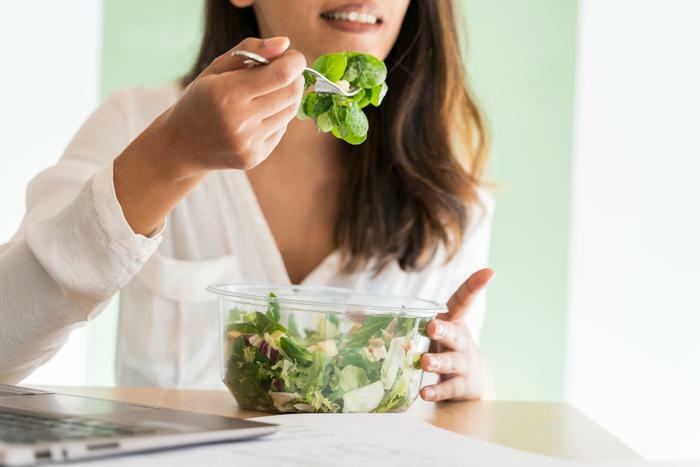 Woman eating salad from container