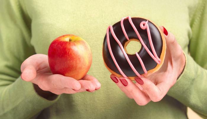 Woman holding apple and donut diet concept 