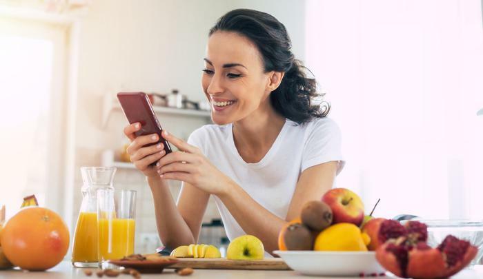 Woman on phone eating fruit