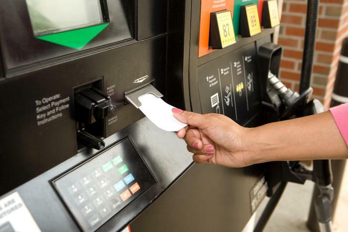 Woman taking gas receipt at pump