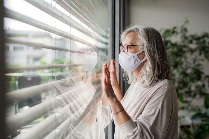 Woman with COVID-19 wearing mask and staring out window