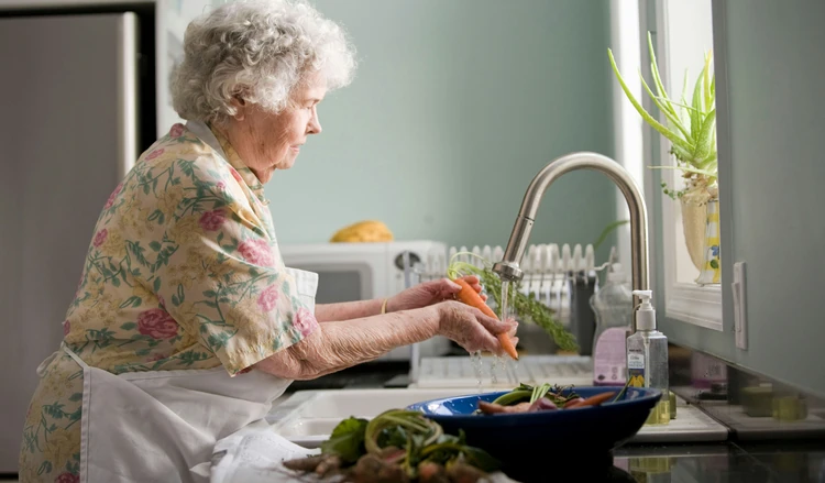 an older woman washing carrots