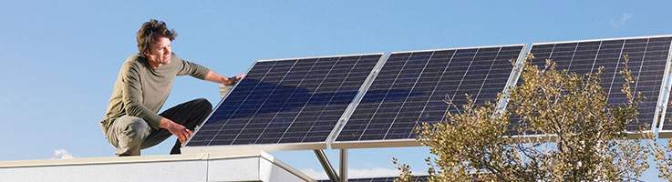 man installing solar panels on roof