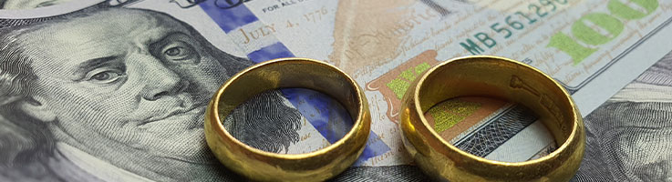 Wedding rings on top of hundred dollar bills