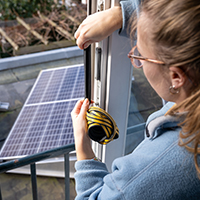 woman sticking draft strips with solar panels on background