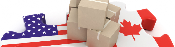 cardboard boxes placed over two large puzzle pieces with the US flag imprinted on one piece and the canadian flag on the other piece