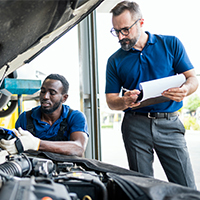 mechanic and manager inspecting car engine
