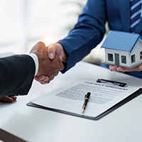 agent and client shake hands after signing papers