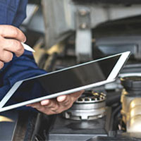 mechanic holding a tablet checking car engine