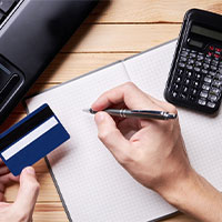 person holding credit card and pen making calculations