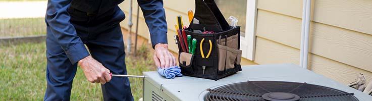 repair technician fixing an air conditioning unit