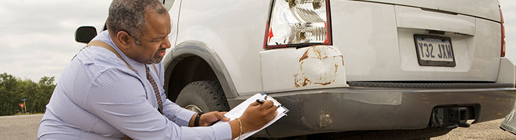 insurance adjuster inspecting damage on car