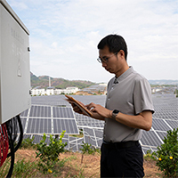 engineer looking at tablet with solar panels on background