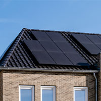 brick house with black solar panels on the roof
