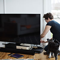 person sitting on a floor next to a tv and dog