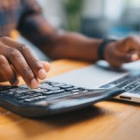 a person making calculations using his calculator and laptop