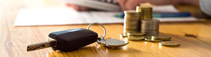 car keys in front of stack of coins