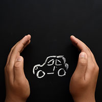 two hands shielding a chalk drawing of a car on a black board