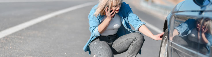 woman experiencing car issues on the road and talking to someone on the phone for help