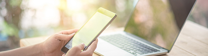 woman on phone next to laptop