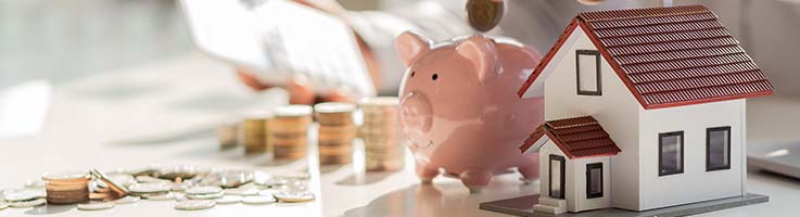 coins being added to piggy bank next to model home