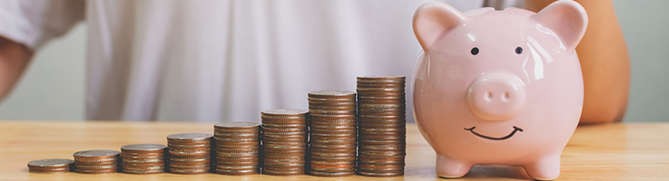 coins stacked next to piggy bank