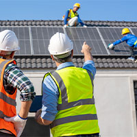 engineers overseeing techs installing solar panels on roof