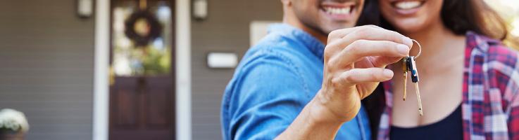couple holding keys in front of new home