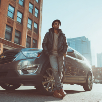 young man leaning against a parked car