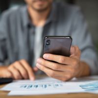 a man seated with his phone reading some documents
