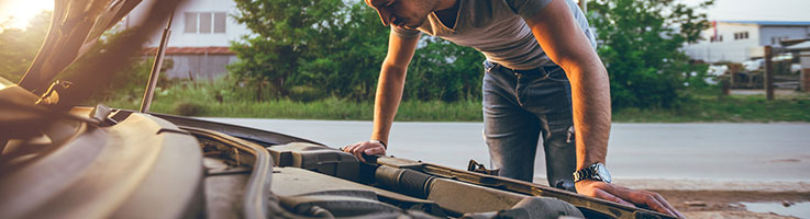 a young man looking under the hood of a car