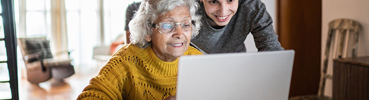 grandson and grandmother using a laptop at home