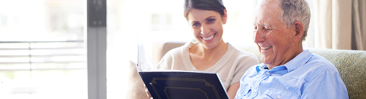 elderly man looking through book with young woman
