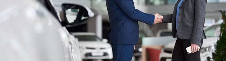 woman shaking hands with car salesman