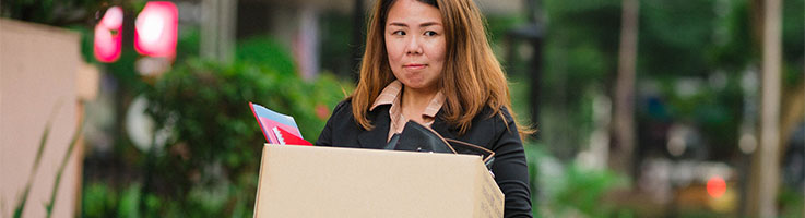 lady carrying box full of personal things leaving office
