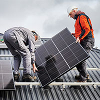 two men installing solar panels on roof