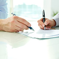 man and woman each holding a pen to sign the same document