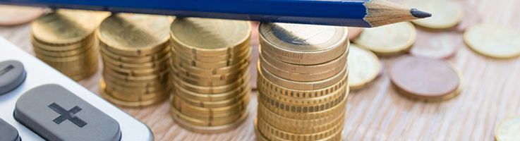 stacks of gold coins with calculator and pencil